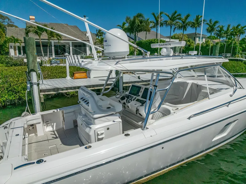 Slide: The Image of 2020 Intrepid 407 Cuddy boat docked near waterfront homes, featuring advanced navigation equipment. - 9