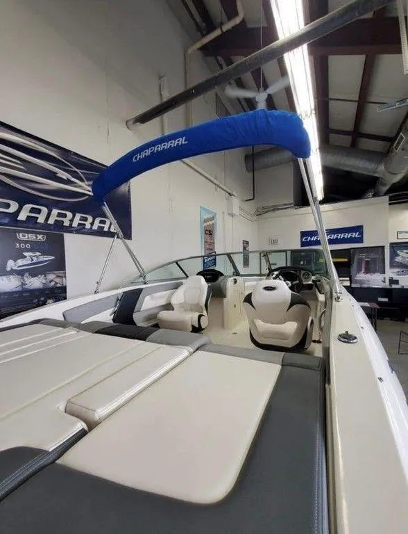 Slide: The Image of 2019 Chaparral 21 H2O OB Sport boat with blue canopy in showroom. - 4