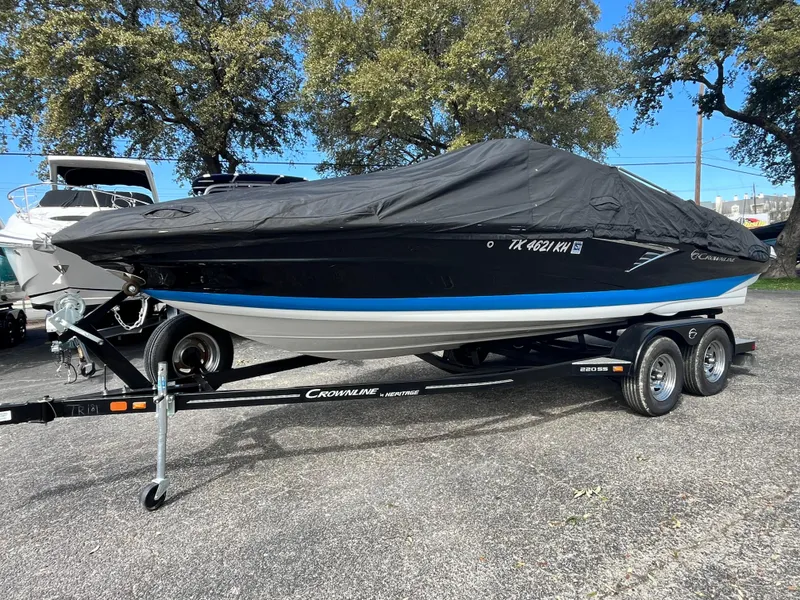 The Image of 2021 Crownline 220SS boat on trailer, covered, parked outdoors. - 1