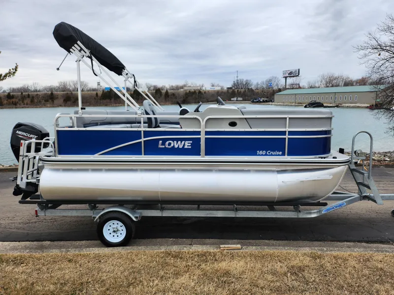 Slide: The Image of 2022 Lowe Ultra 160 Cruise pontoon boat on trailer by a lake. - 10