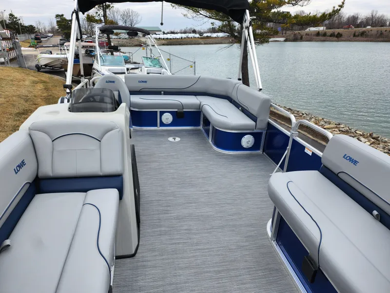 Slide: The Image of 2022 Lowe Ultra 160 Cruise pontoon boat with spacious seating, docked by a serene lake. - 11