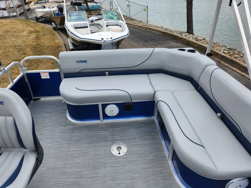 Slide: The Image of 2022 Lowe Ultra 160 Cruise pontoon boat with gray seating and blue accents by the water. - 15