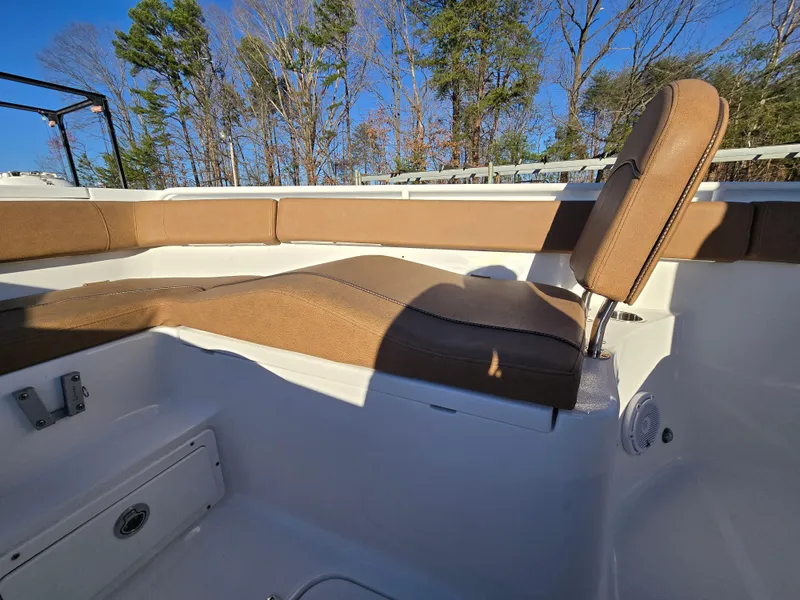 Slide: The Image of 2022 Sea Hunt Ultra 255 SE boat interior with tan seating, surrounded by trees. - 17