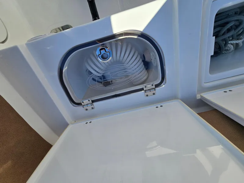 Slide: The Image of 2022 Sea Hunt Ultra 255 SE boat storage compartment with coiled hose. - 38