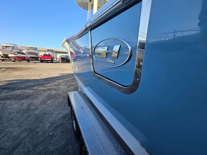 Slide: The Image of 2022 Sea Hunt Ultra 255 SE boat side view with logo, parked outdoors. - 5