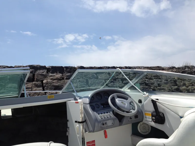 Slide: The Image of 1996 Sea Ray 240 Overnighter boat interior with steering wheel and dashboard, under a clear sky. - 5