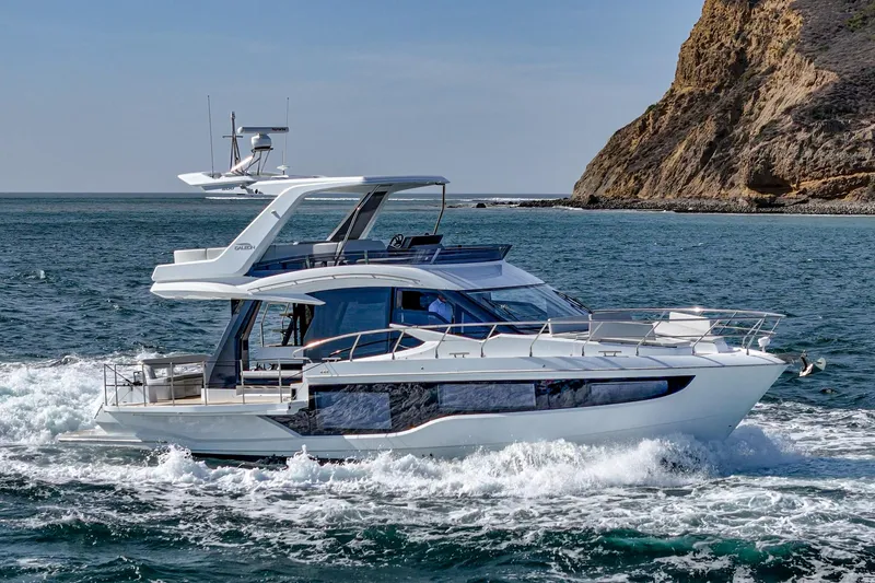 The Image of 2025 Galeon 500 Fly yacht cruising near rocky coastline. - 0