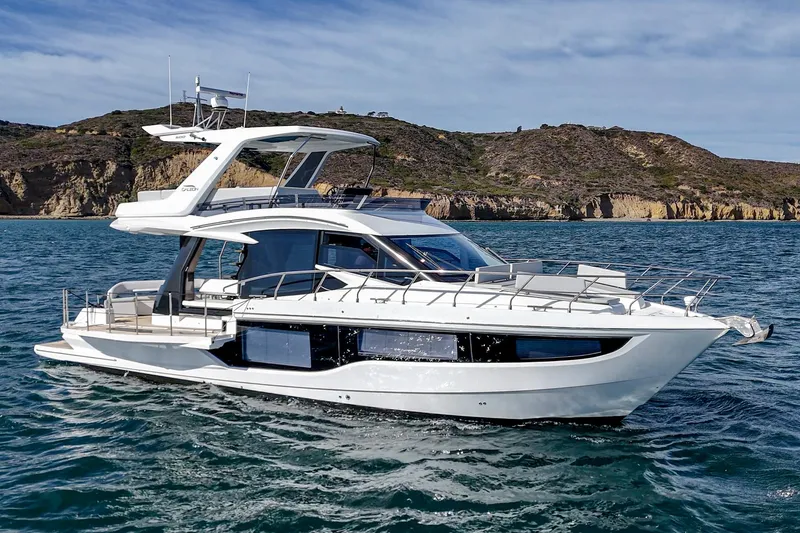 Slide: The Image of 2025 Galeon 500 Fly yacht cruising on the ocean with scenic cliffs in the background. - 17