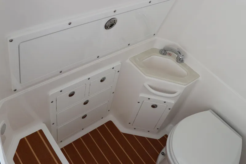 Slide: The Image of 2025 Edgewater 325CC boat interior with compact bathroom, featuring a toilet and sink. - 49