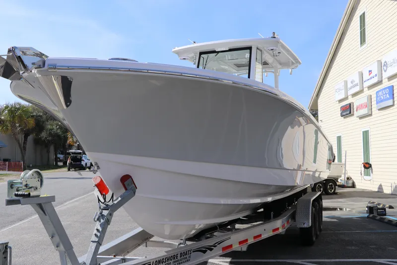 Slide: The Image of 2025 Edgewater 325CC boat with dual outboard engines, parked in a lot. - 7