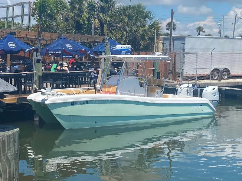 Slide: The Image of 2023 Prowler 25 boat docked near waterfront restaurant with blue umbrellas. - 13