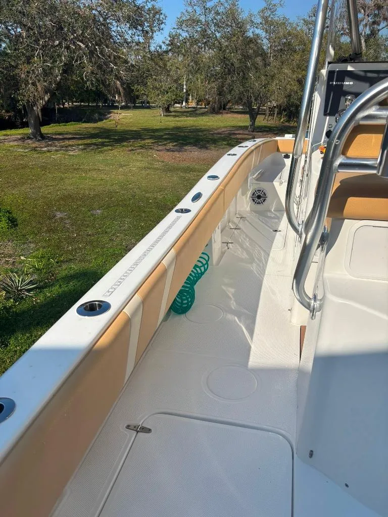 Slide: The Image of 2023 Prowler 25 boat interior with seating and railing, set in a grassy area. - 35