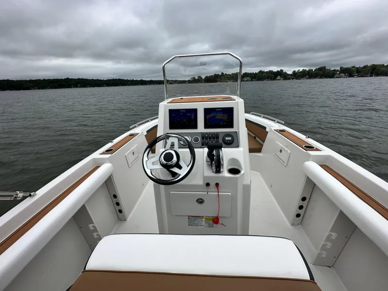Slide: The Image of 2025 Starcraft SVX 211 OB CC boat interior with steering wheel and control panel on a lake. - 24