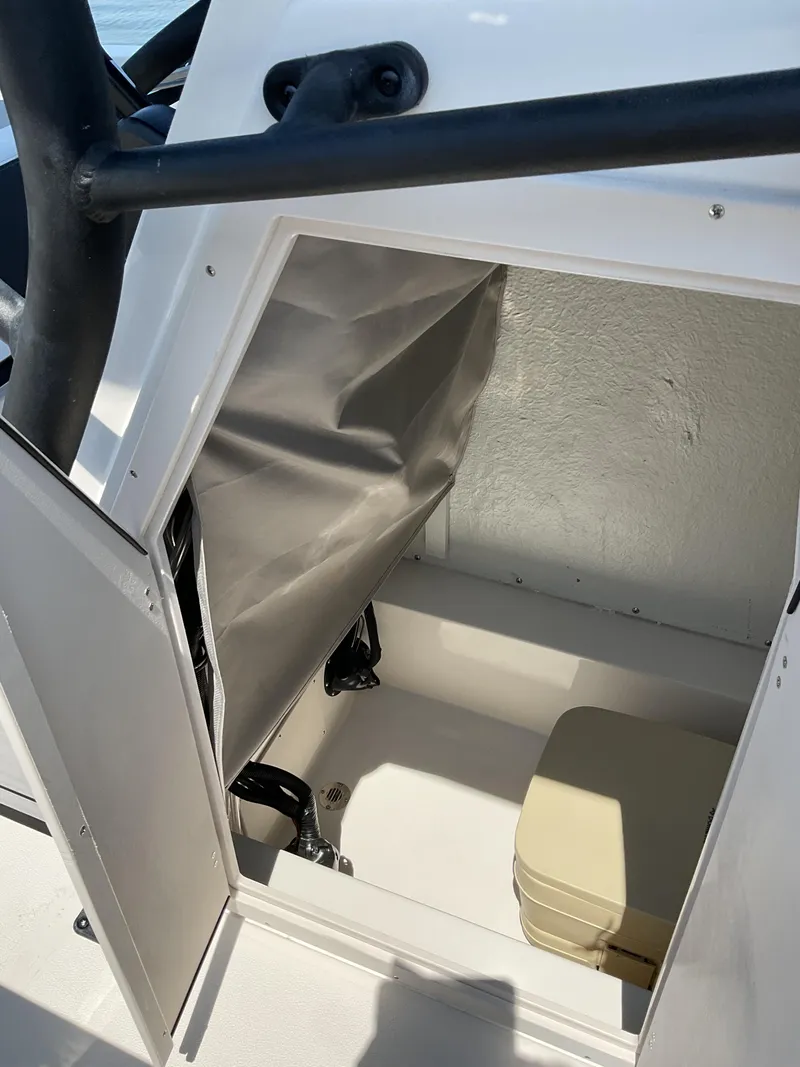 Slide: The Image of 2025 Starcraft SVX 211 OB CC boat storage compartment with beige portable toilet. - 7
