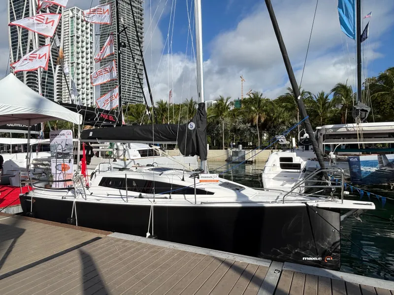 Slide: The Image of 2025 Maxus 26 sailboat docked at marina with cityscape background. - 0
