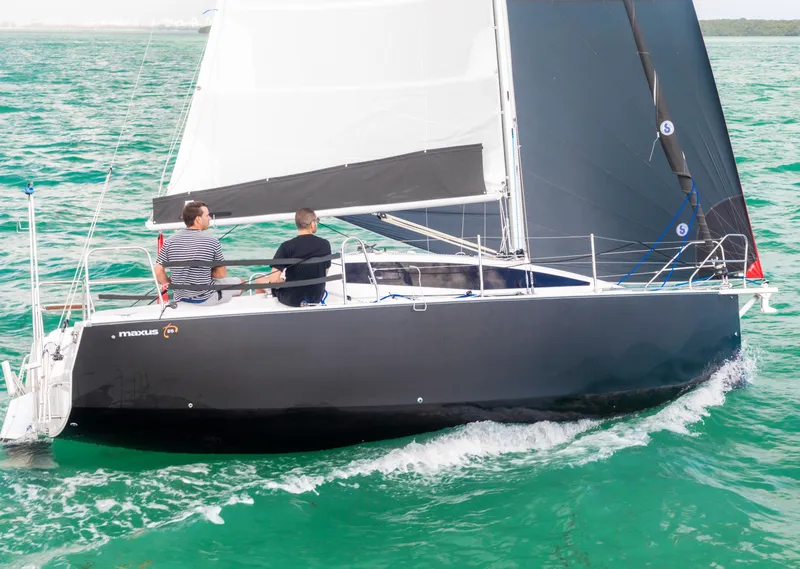 Slide: The Image of 2025 Maxus 26 sailboat navigating turquoise waters with two people onboard. - 7