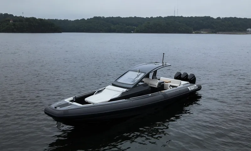 Slide: The Image of 2024 Pirelli 42 OB boat on calm lake with forested shoreline. - 1