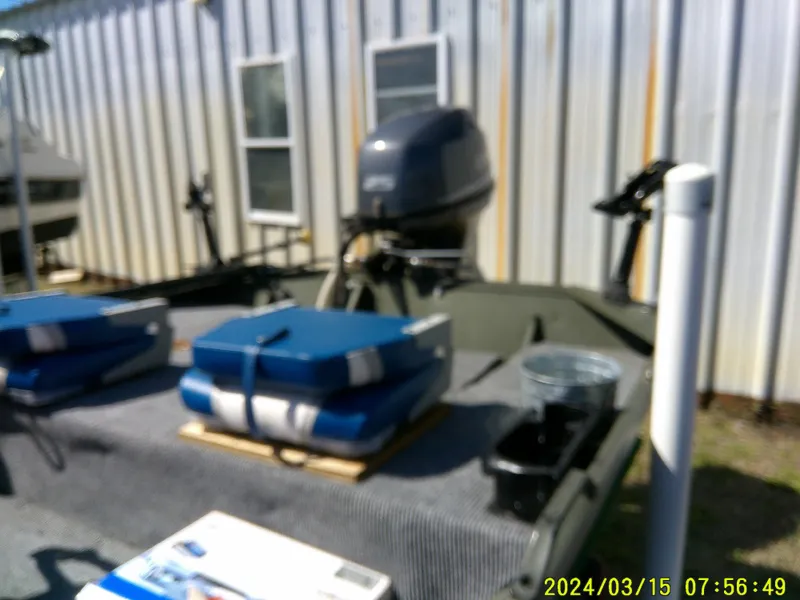 Slide: The Image of 2018 Alumacraft 1648 Jon boat with motor, outdoor setting, blue seats, and equipment. - 10