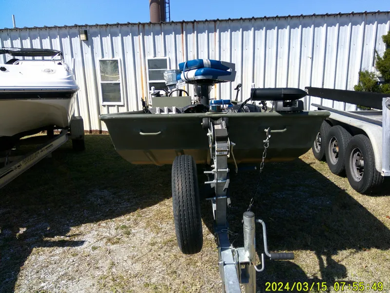 Slide: The Image of 2018 Alumacraft 1648 Jon boat on trailer, parked outdoors near a building. - 2