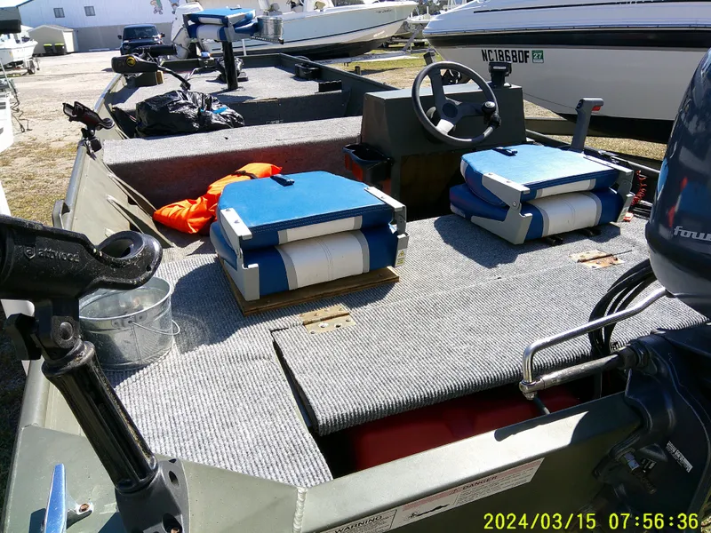 Slide: The Image of 2018 Alumacraft 1648 Jon boat with seating and steering wheel, parked outdoors. - 7