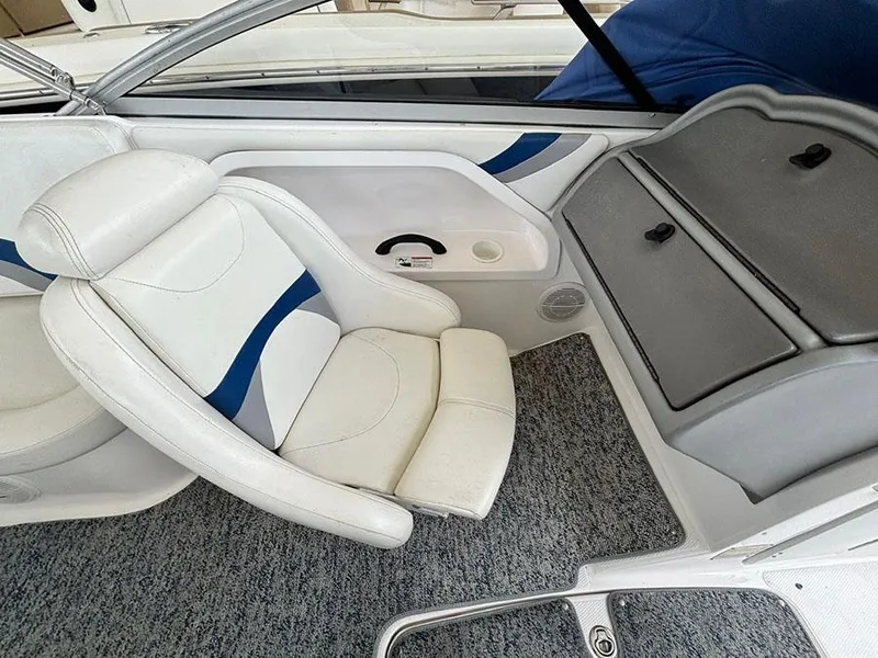 Slide: The Image of 2004 Yamaha Boats 230 SX interior with white and blue seating, gray storage, and carpeted flooring. - 10