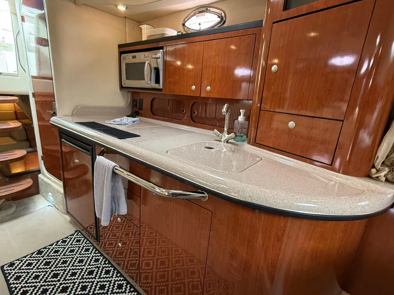 Slide: The Image of Luxurious 2007 Sea Ray 340 Sundancer yacht interior kitchen with wood cabinetry and modern appliances. - 25