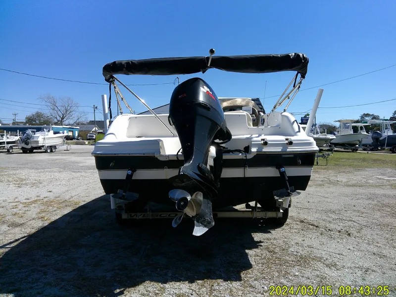 Slide: The Image of 2006 Hurricane Fun Deck 194 boat with outboard motor, parked outdoors. - 9