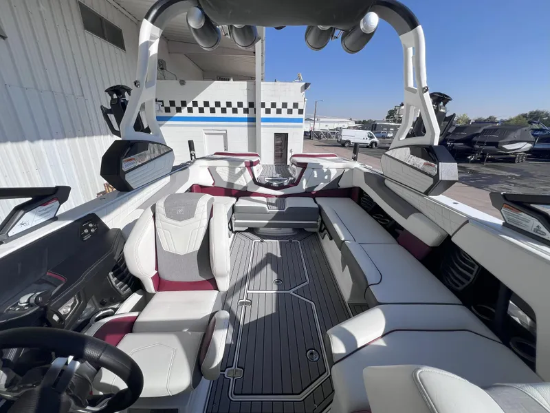 Slide: The Image of 2021 Nautique Super Air G23 boat interior with white and maroon seating, docked outdoors. - 14
