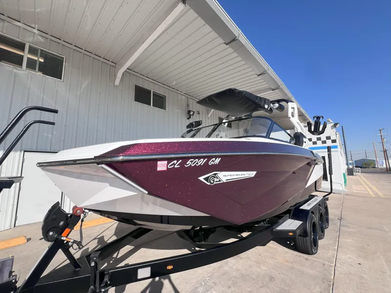 Slide: The Image of 2021 Nautique Super Air G23 boat on trailer, parked outside a building. - 2