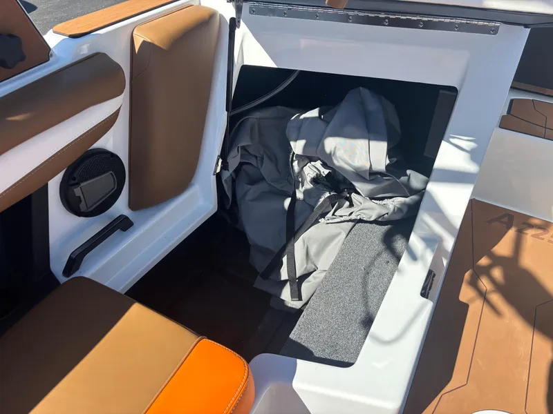 Slide: The Image of 2025 Axis A225 boat interior storage compartment with brown seating and speaker. - 10