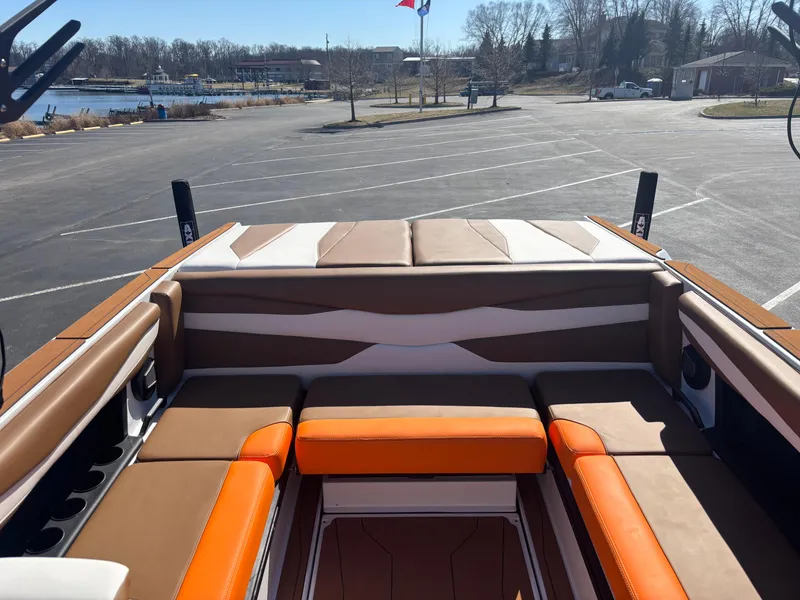 Slide: The Image of 2025 Axis A225 boat interior with orange and brown seating, parked near a waterfront. - 11