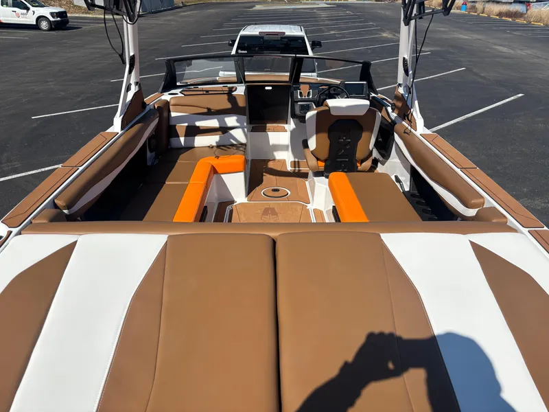 Slide: The Image of 2025 Axis A225 boat interior with brown and white seating, parked in a lot. - 3