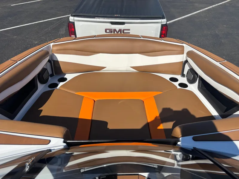 Slide: The Image of 2025 Axis A225 boat interior with brown and orange seating, parked near a GMC vehicle. - 6