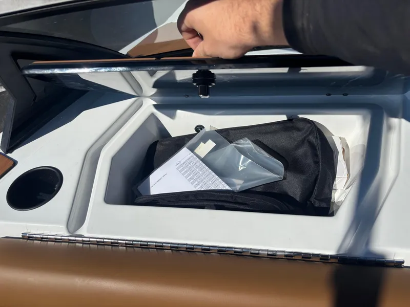 Slide: The Image of Open storage compartment in 2025 Axis A225 boat with documents and bag inside. - 9