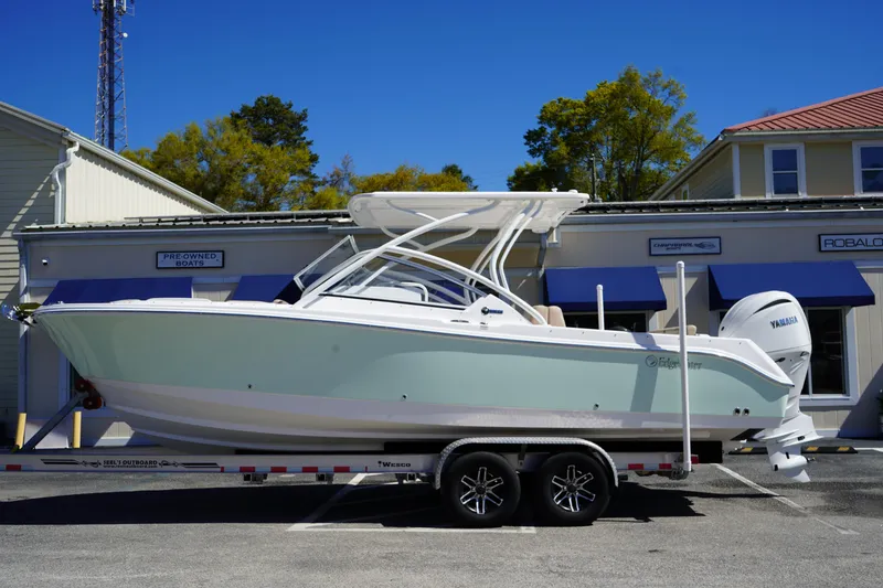 The Image of 2025 Edgewater 248 CX boat on trailer, parked outside a building under clear blue sky. - 0