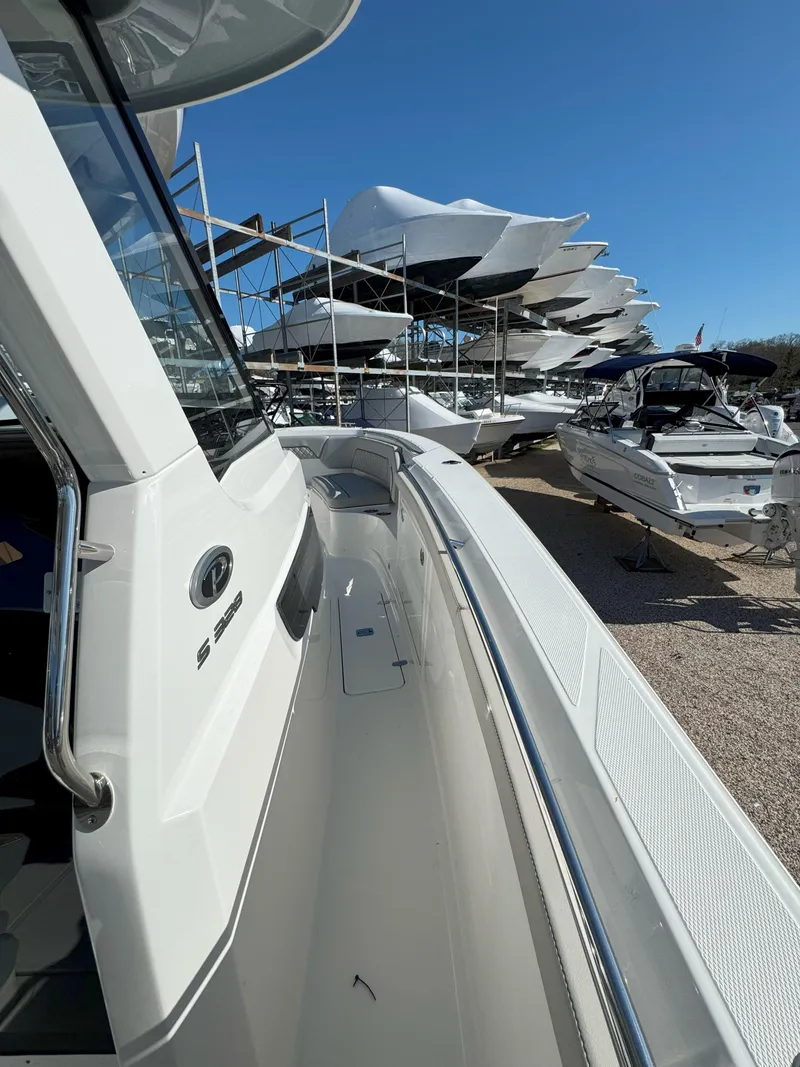 Slide: The Image of 2025 Pursuit S 328 boat docked, surrounded by other boats under clear blue sky. - 31