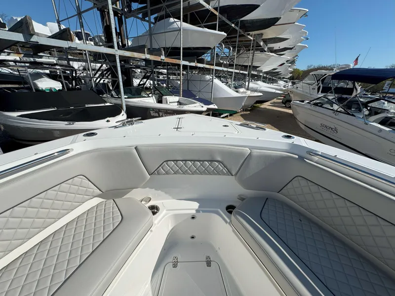 Slide: The Image of Bow seating area of 2025 Pursuit S 328 boat, with diamond-stitched upholstery, docked among other boats. - 33
