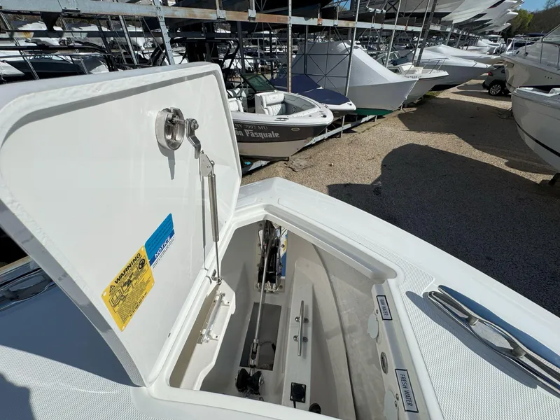 Slide: The Image of 2025 Pursuit S 328 boat with open storage compartment, docked among other boats. - 35