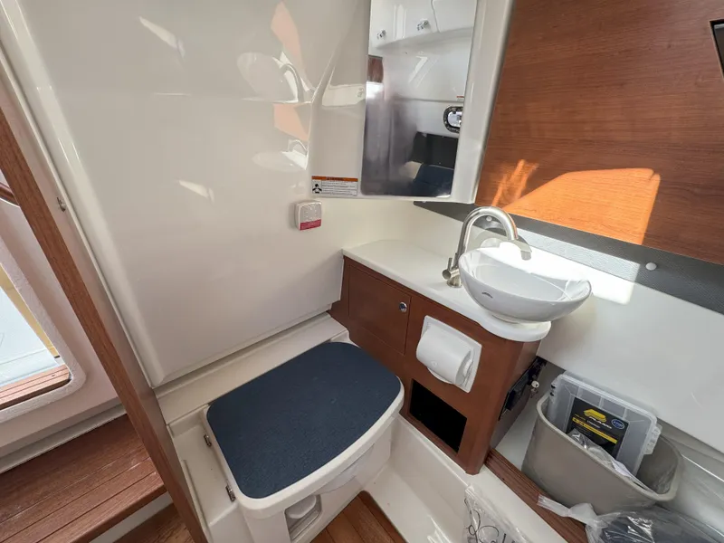 Slide: The Image of 2025 Pursuit S 328 boat interior bathroom with sink, toilet, and wooden accents. - 38