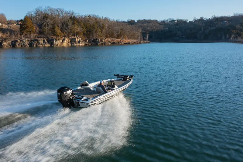 Slide: The Image of A 2017 Phoenix 618 Pro boat speeding on a serene lake with wooded shoreline. - 0