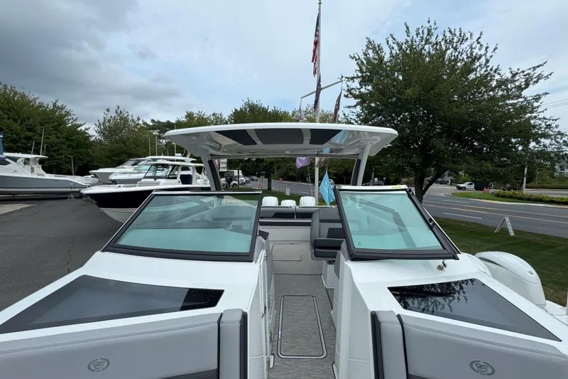 Slide: The Image of 2025 Cobalt R33 OB boat with sleek design, docked near other boats, trees in background. - 26