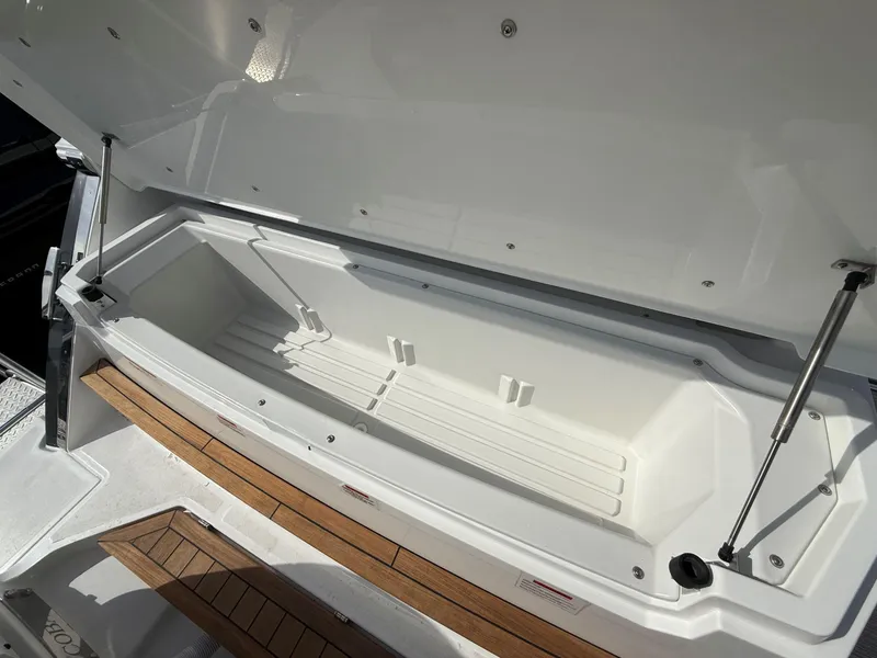 Slide: The Image of Open storage compartment in 2025 Cobalt R33 OB boat, featuring sleek white interior design. - 7
