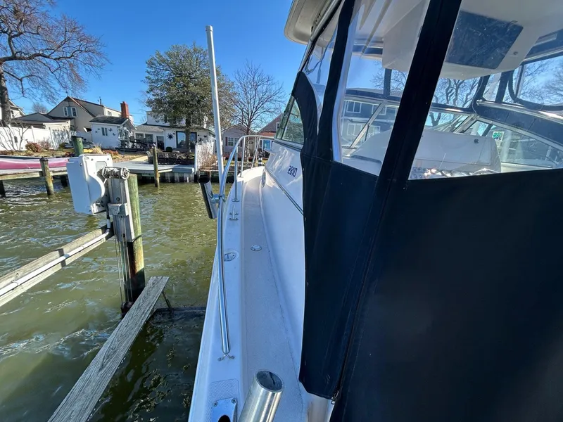 Slide: The Image of 1997 Pro-Line 2810 Walkaround boat docked by waterfront homes on a sunny day. - 11