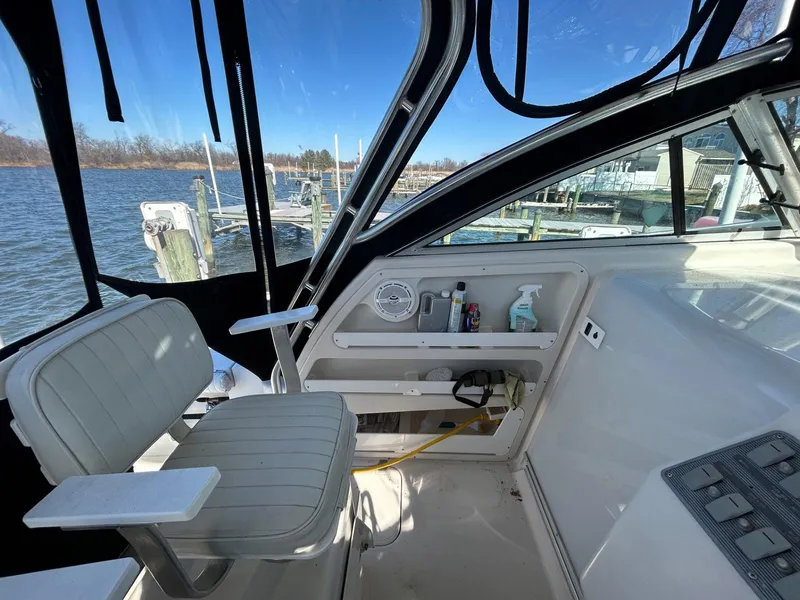 Slide: The Image of 1997 Pro-Line 2810 Walkaround boat interior with seating and storage, docked by the water. - 15