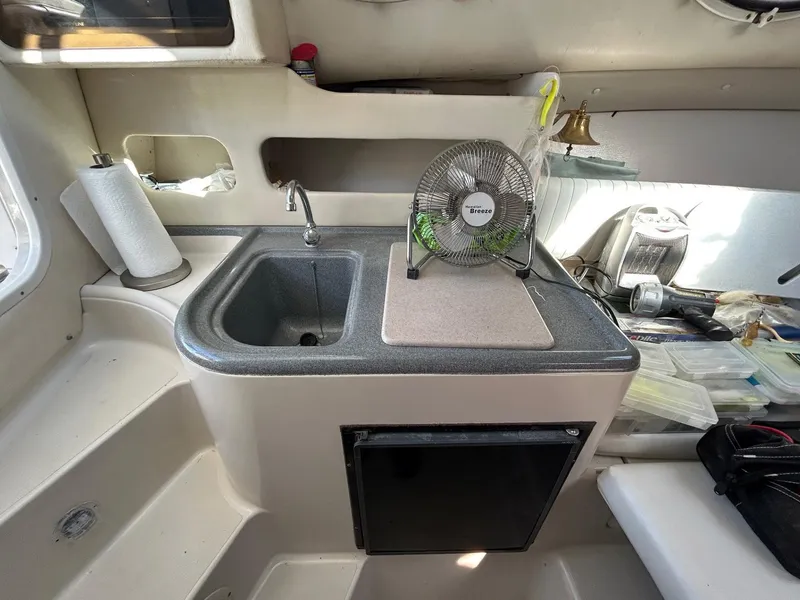 Slide: The Image of 1997 Pro-Line 2810 Walkaround boat interior with sink, fan, and storage area. - 23