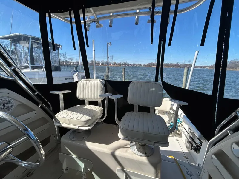 Slide: The Image of 1997 Pro-Line 2810 Walkaround boat interior with two swivel seats, docked by the water. - 28