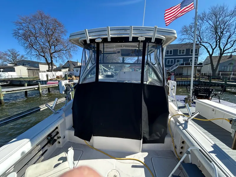 Slide: The Image of 1997 Pro-Line 2810 Walkaround boat docked, featuring a covered cockpit and American flag. - 8