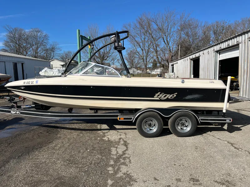 Slide: The Image of 2000 Tigé 2100V Limited boat on trailer, parked outdoors near metal buildings. - 7