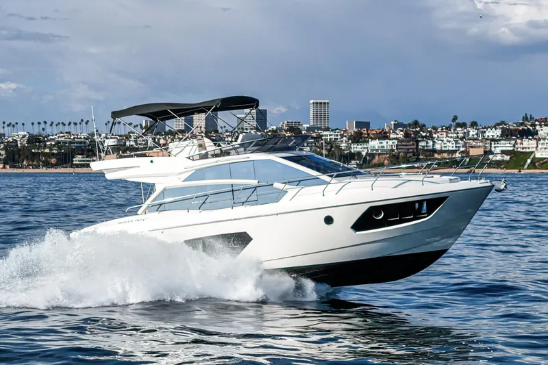 Slide: The Image of 2019 Absolute 45 FLY yacht cruising on open water near coastal cityscape. - 1