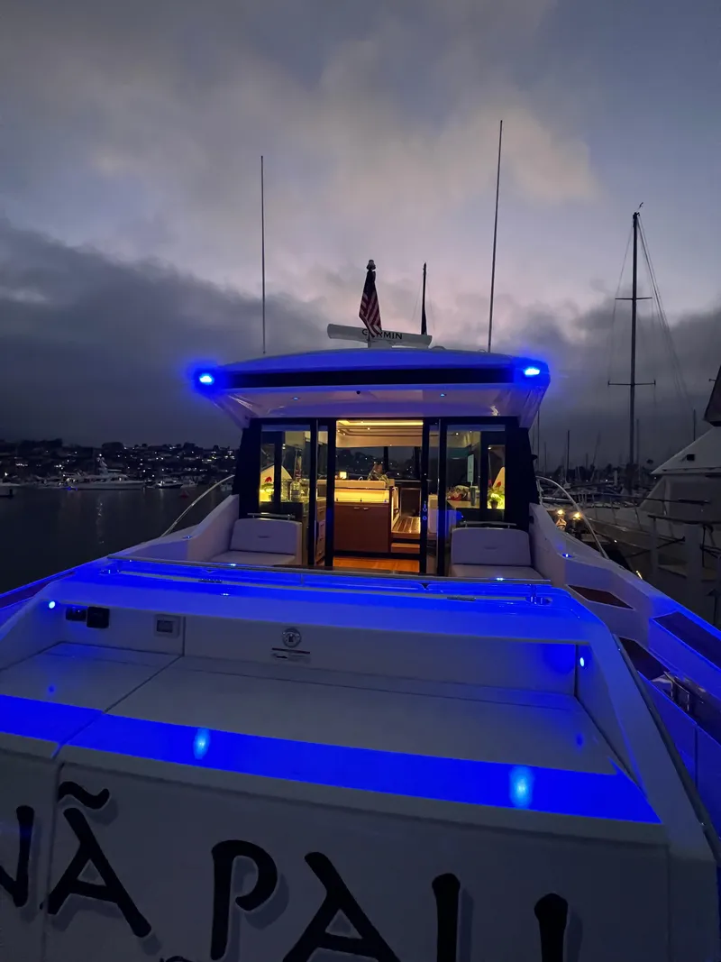 Slide: The Image of 2021 Tiara Yachts 53 Coupe illuminated at dusk with blue lights, docked in a marina. - 10